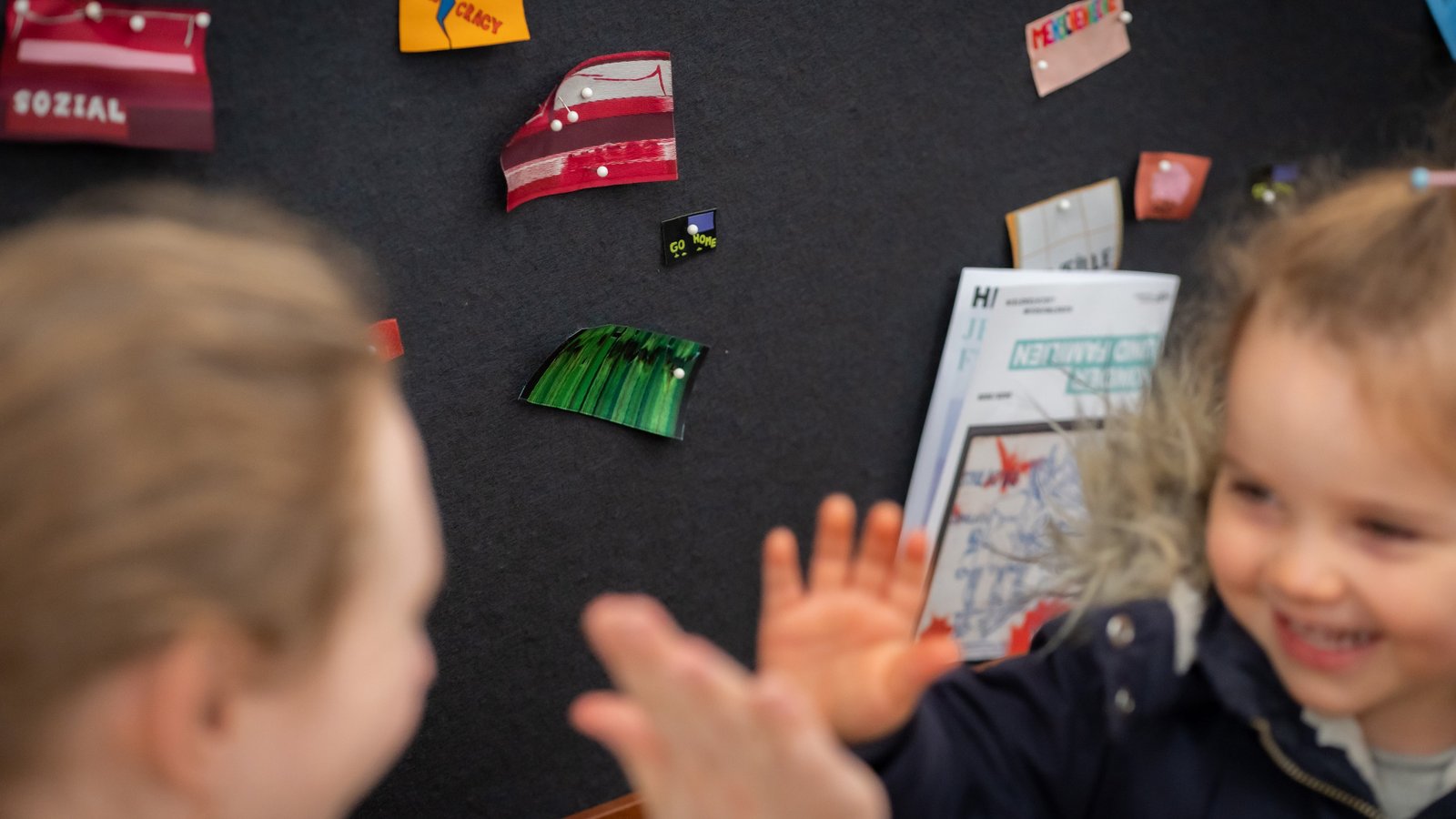 2 Kinder vor einer Pin Wand mit verschiedenen bunten Zetteln
