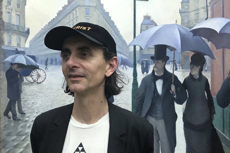 Mann vor einem Gemälde mit Regenschirmen