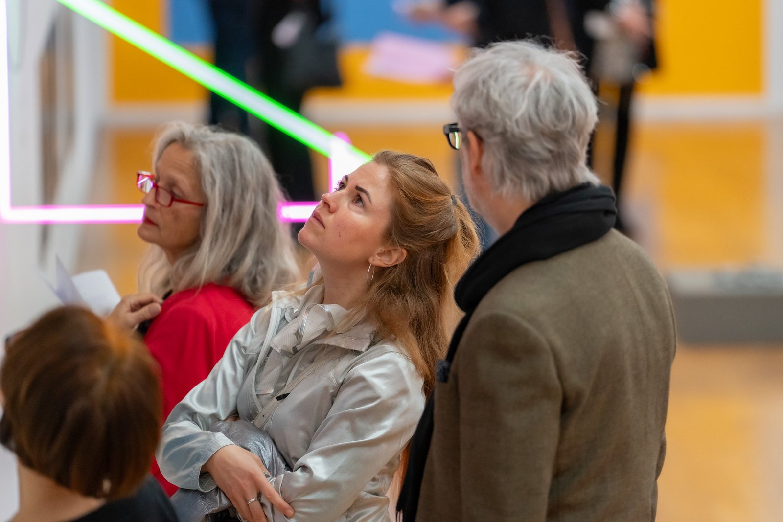 Eine Gruppe von Menschen betraut eine Ausstellung mit leuchtenden Neonröhren.