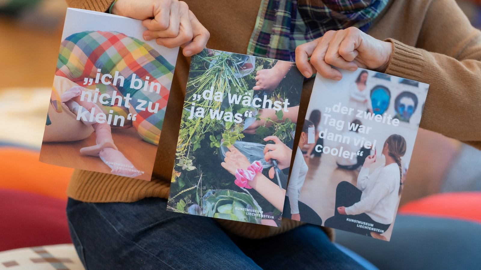 Person hält Broschüren des Kunstmuseums Liechtenstein