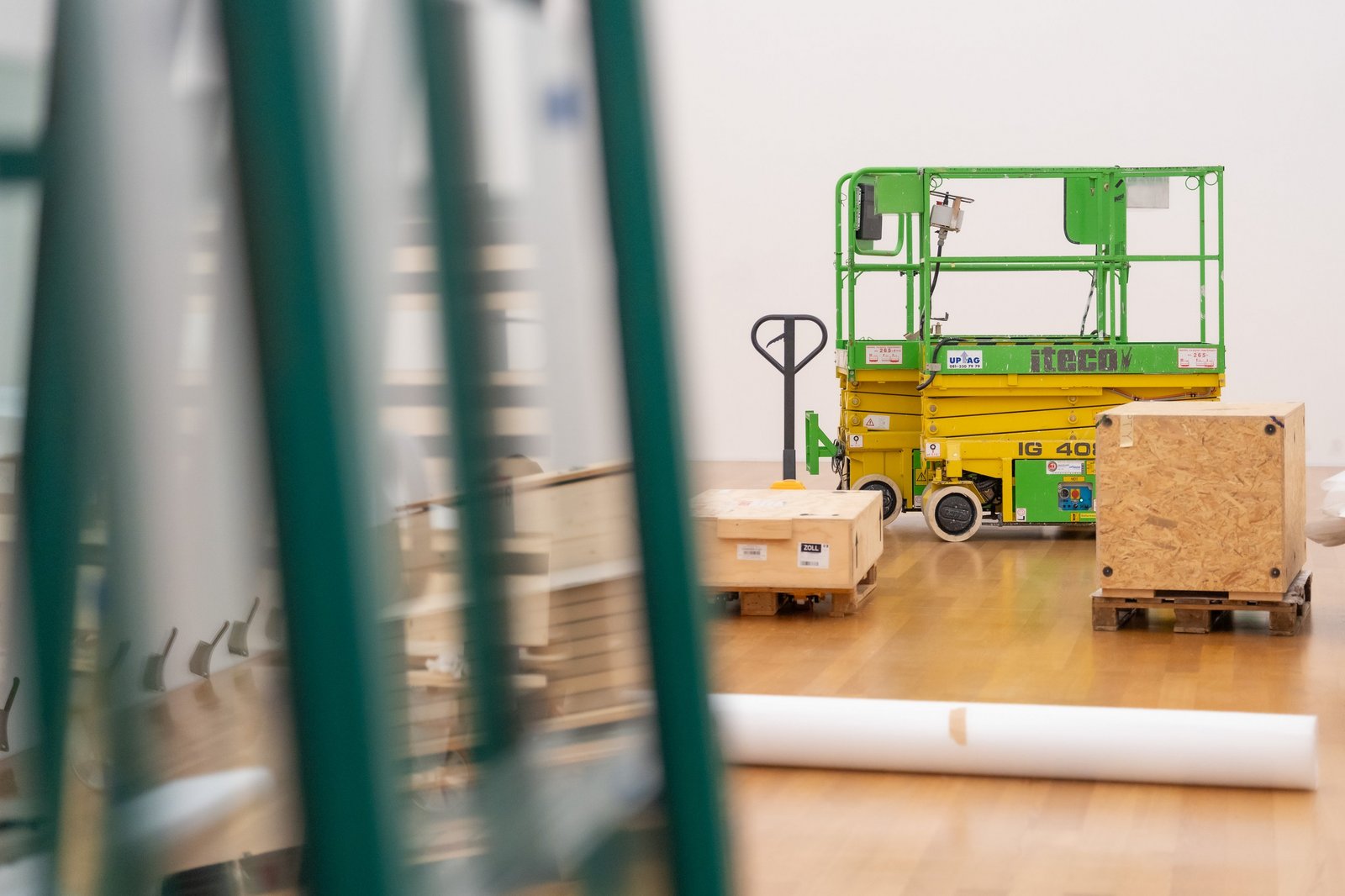 Eine Hebebühne, Holzkisten und weiteres Material in einem Ausstellungssaal
