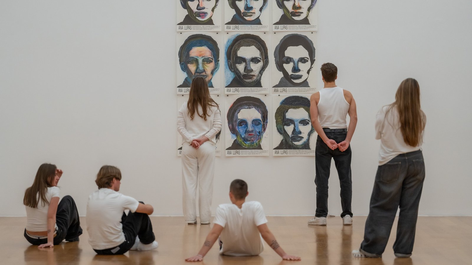 Besuchende betrachten Porträts in einer Ausstellung