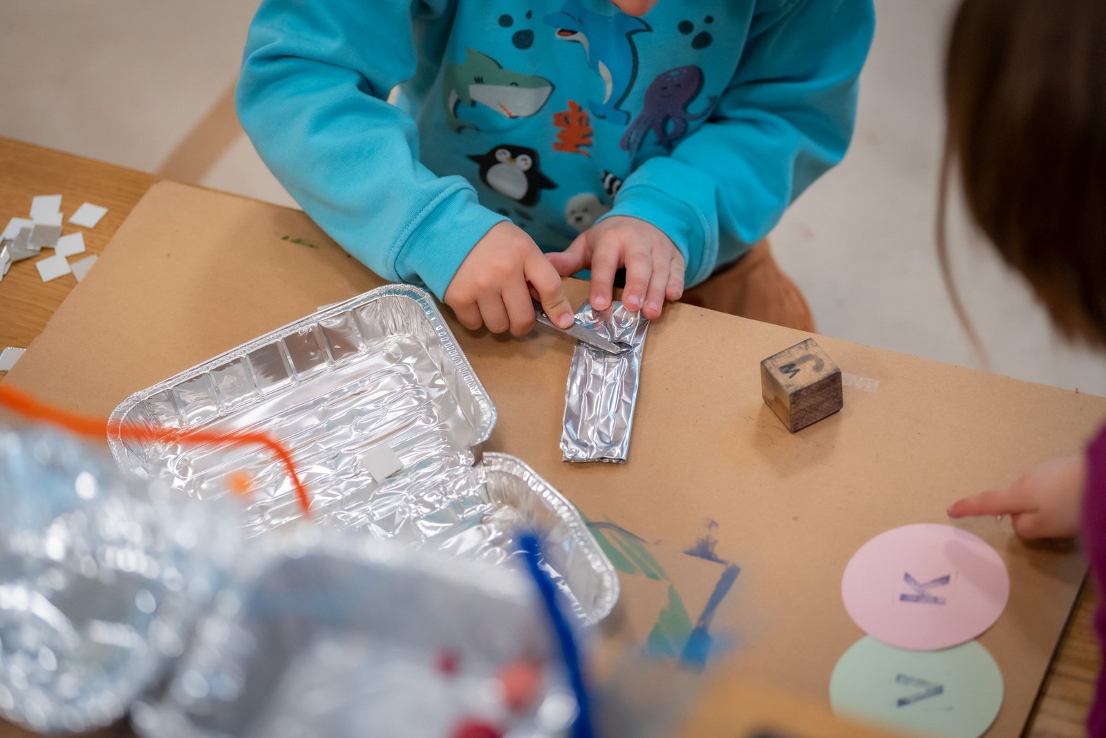 Zwei Kinder an einem Tisch im Museums-Atelier, die mit verschiedenen Materialien gestalten