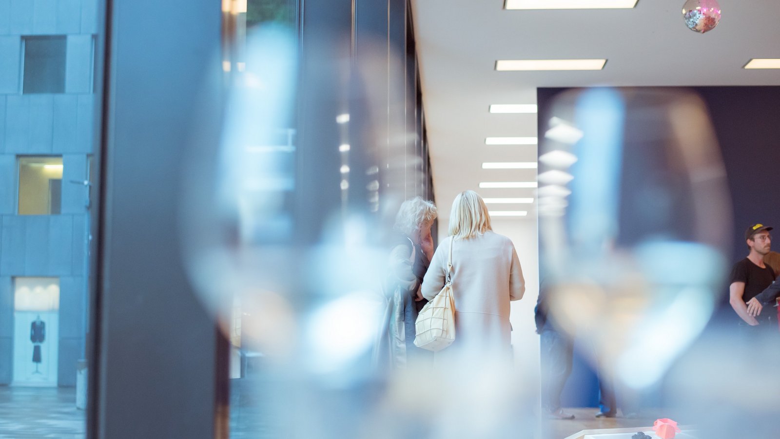 Event-Gäste durch unscharfe Weingläser fotografiert.