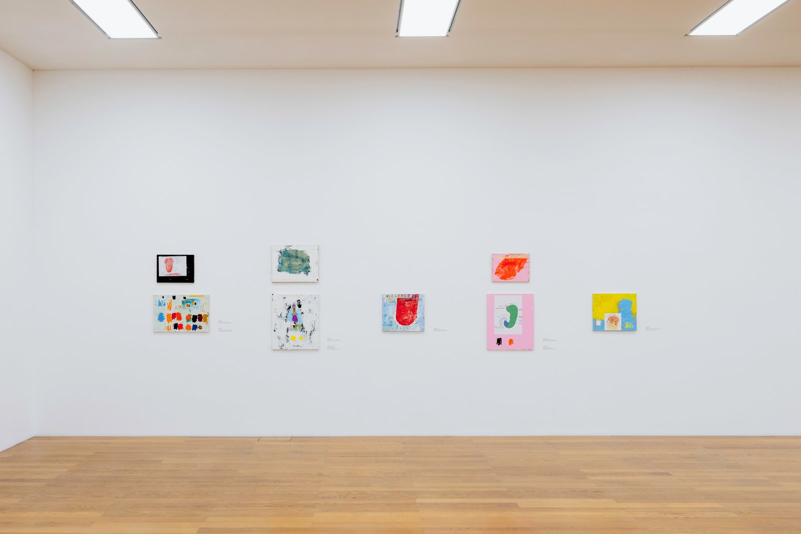 Ausstellungsraum mit acht Kunstwerken an einer Wand