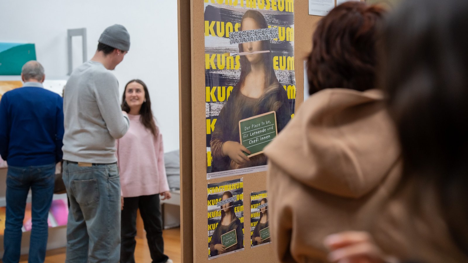 Besuchende in einer Ausstellung mit Plakatwand