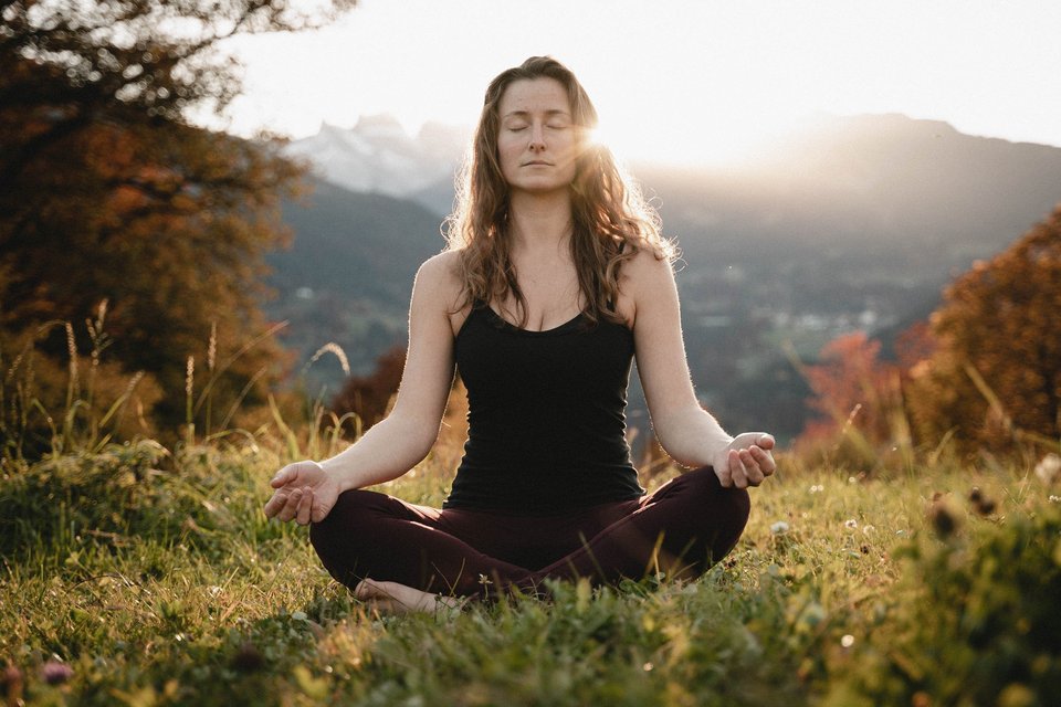 Eine Frau macht Yoga bei einer Berglandschaft
